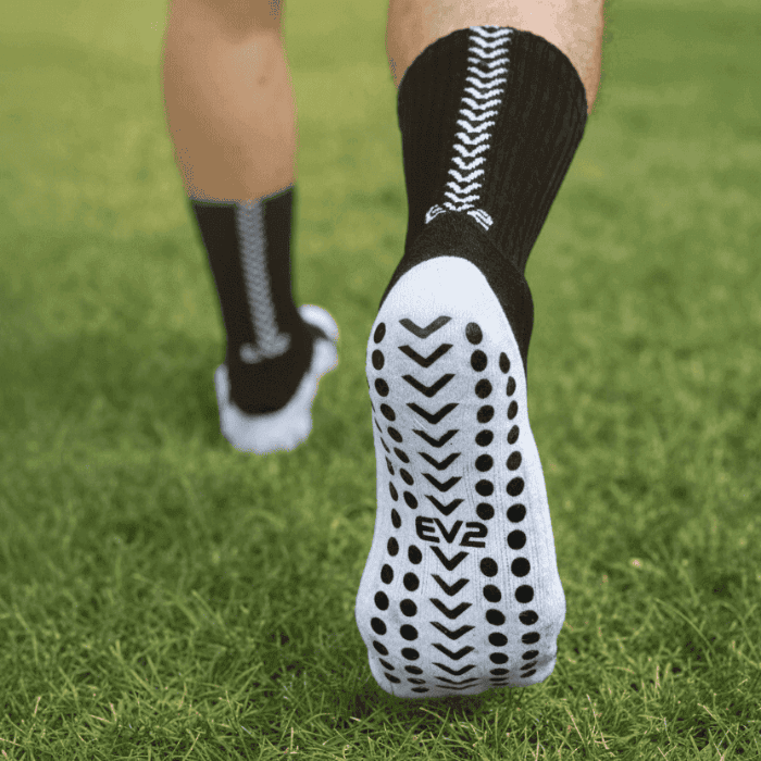EV2 Black Grip Socks with white sole on grassy field pictured from the sole of the foot