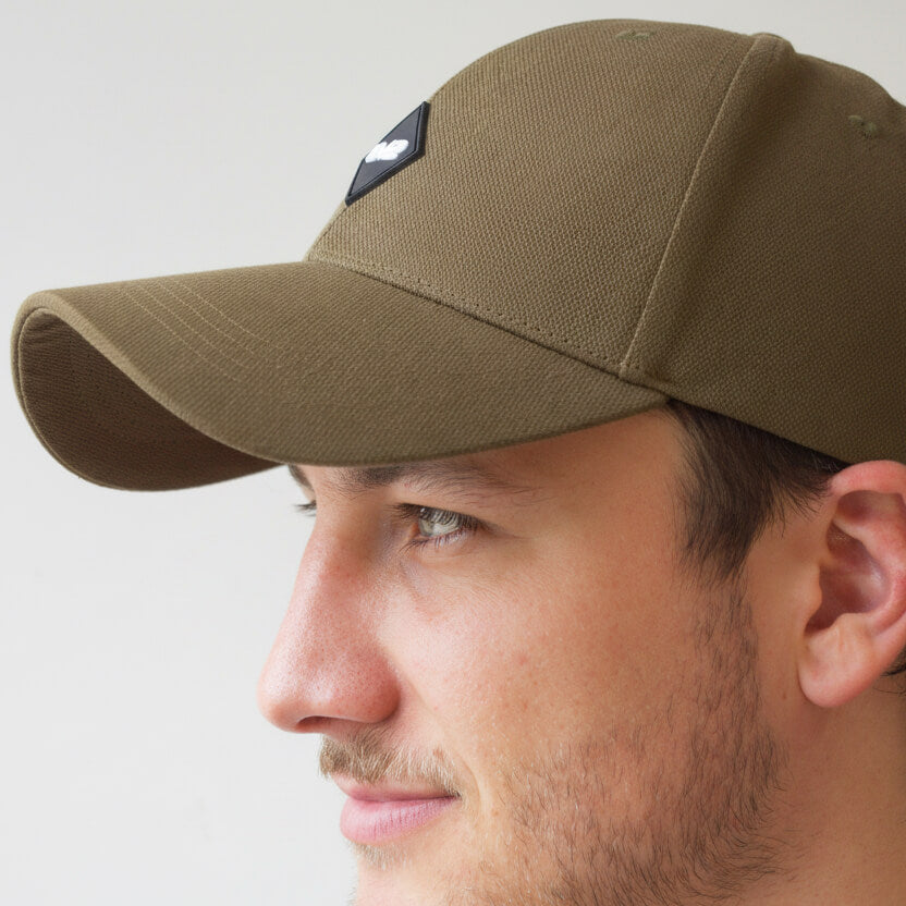 Man wearing an olive cap with an EV2 Logo on a plain background