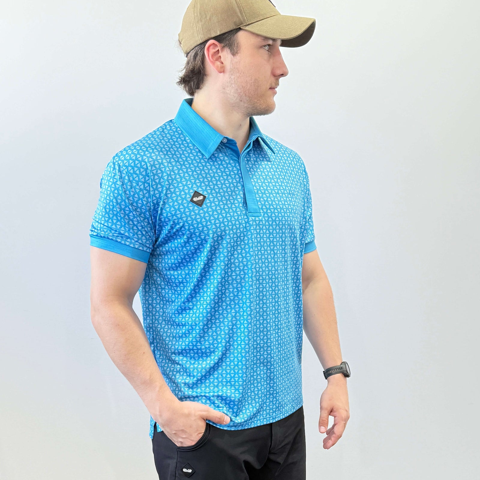 Person wearing a Blue and light blue EV2 Diamond patterned golf shirt and black golf shorts standing in front of a white background.