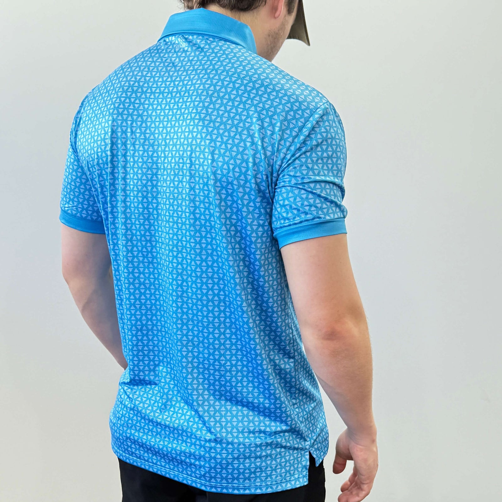 Person wearing a Blue and light blue EV2 Diamond patterned golf shirt and black golf shorts standing in front of a white background.