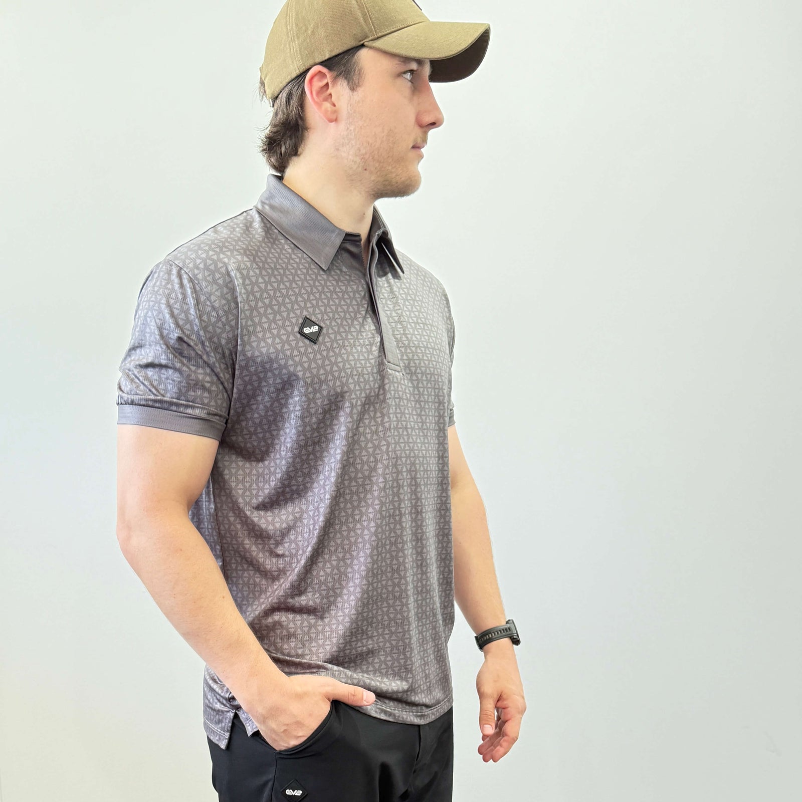 Person wearing a Charcoal and Grey EV2 Diamond patterned golf shirt and black golf shorts standing in front of a white background.
