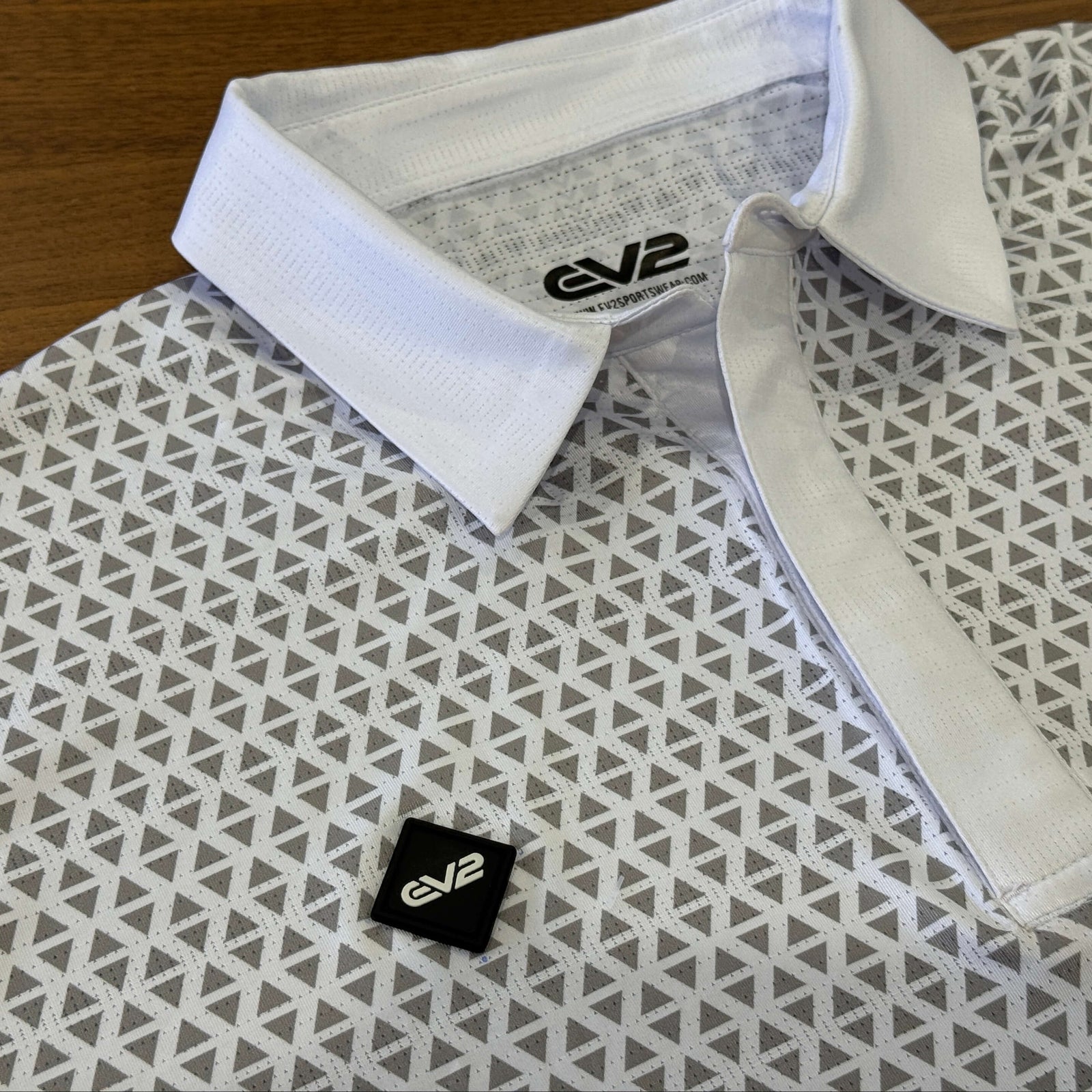 Back EV2 rubber logo close up of Diamond golf polo in white and grey, featuring the collar of the golf shirt.