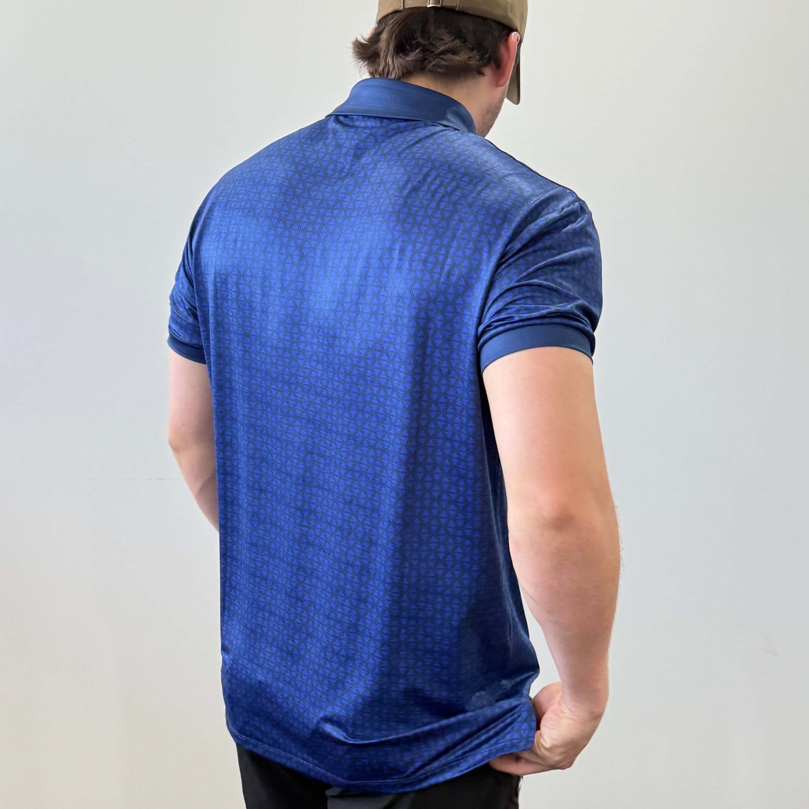 Person wearing a Navy and Blue EV2 Diamond patterned golf shirt and black golf shorts standing in front of a white background.