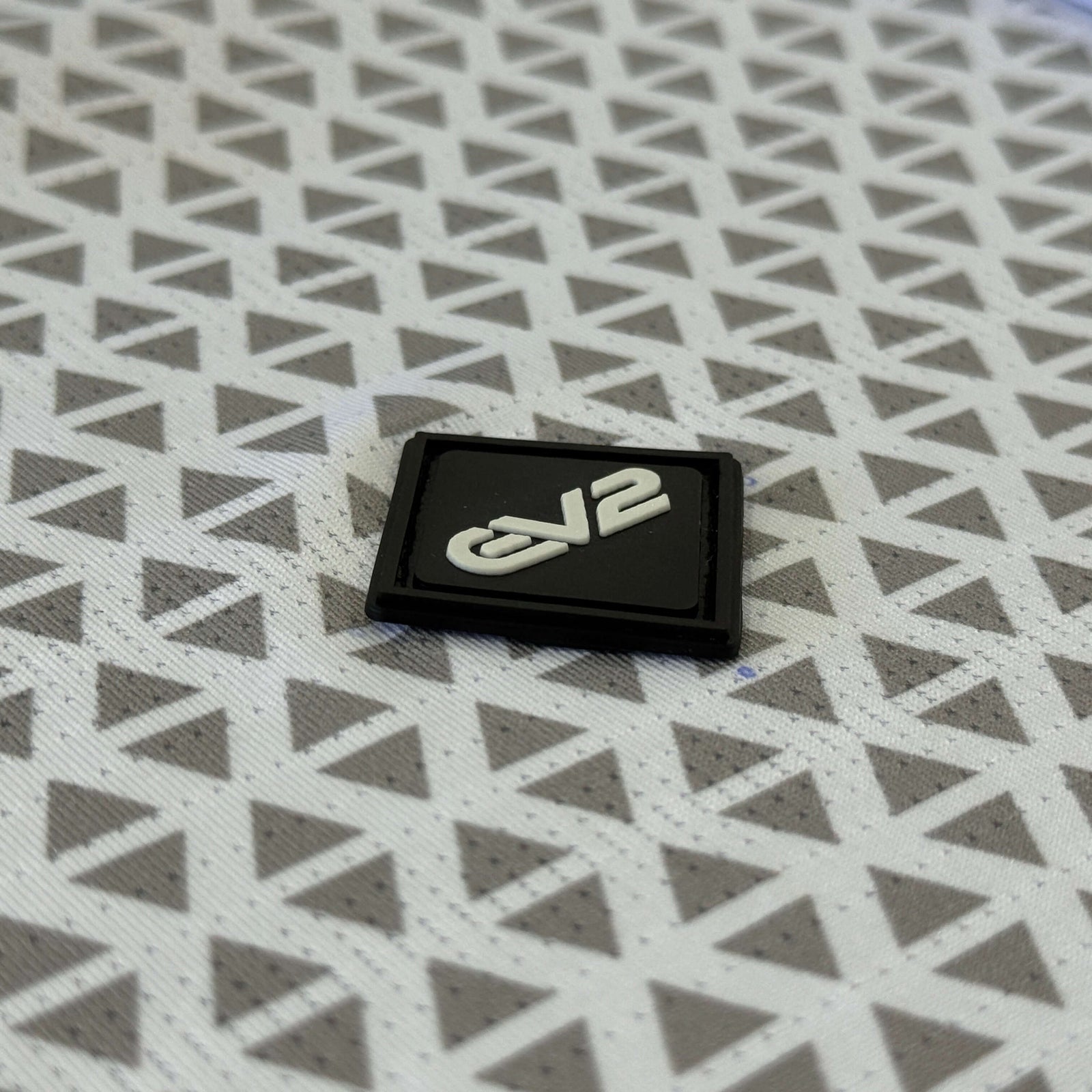 Back EV2 rubber logo close up of Diamond golf polo in white and grey. 