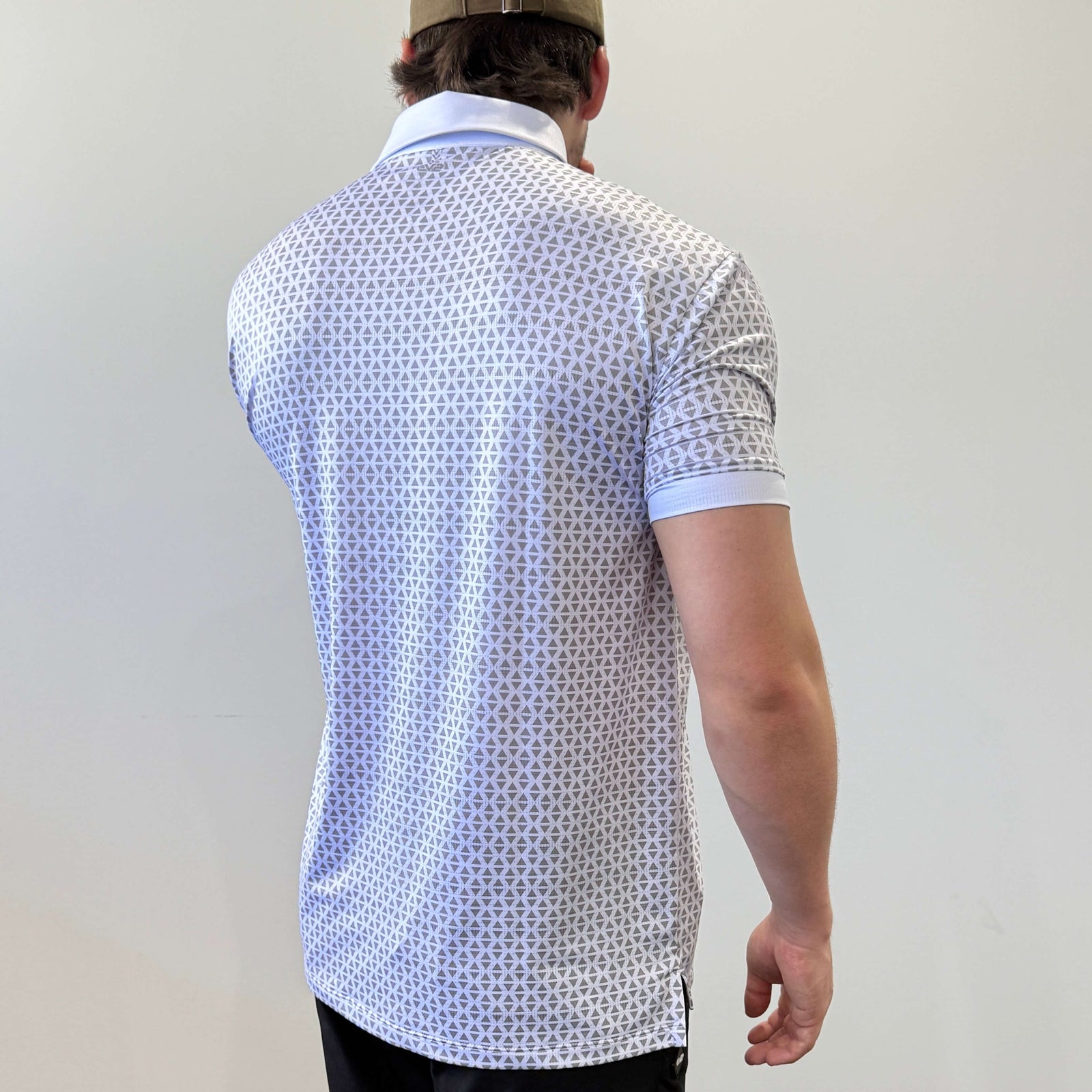 Person wearing a white and grey EV2 Diamond patterned golf shirt and black golf shorts standing in front of a white background.