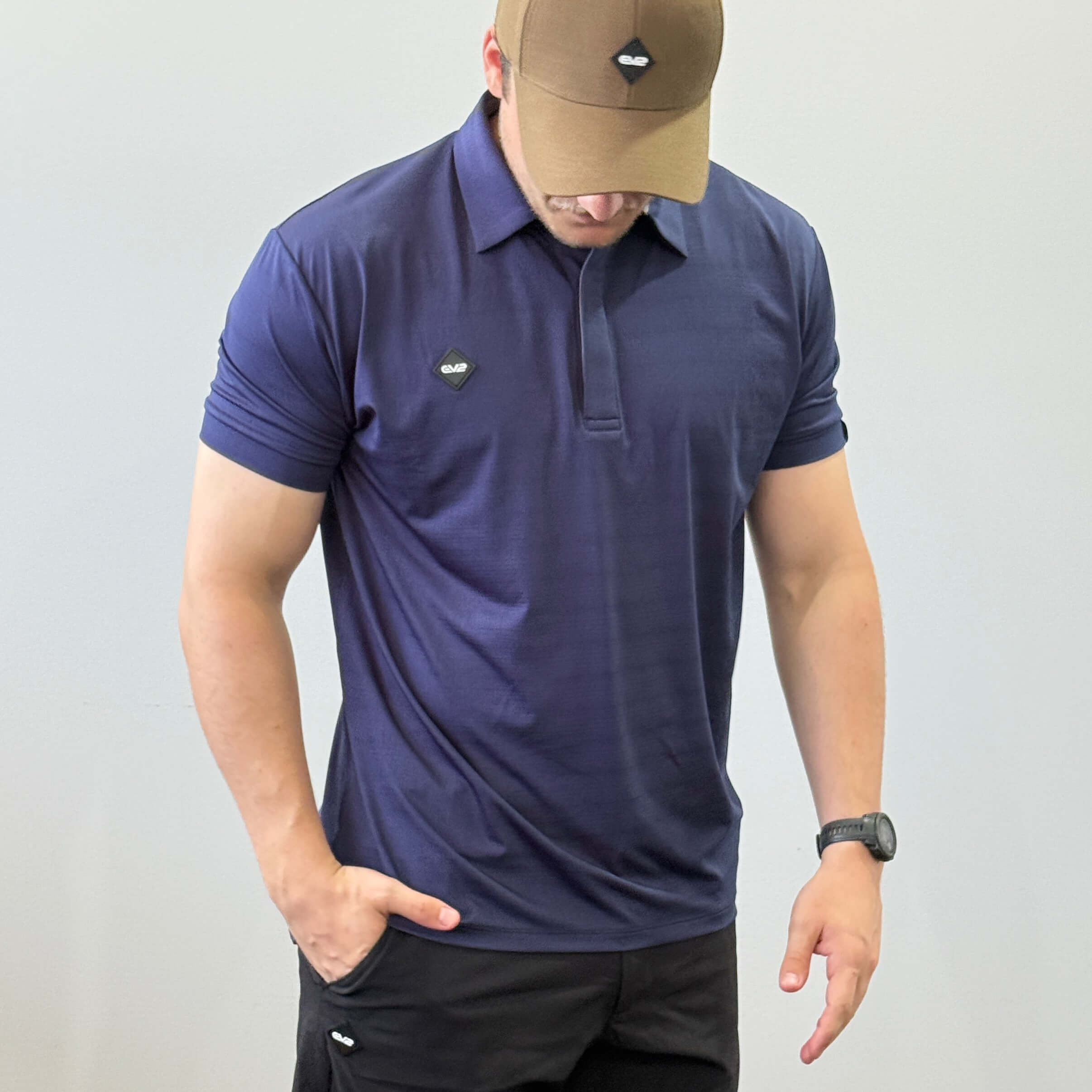 EV2 Masters Polo in bright red with a black rubber logo in the shape of a diamond. Model is also wearing black EV2 golf shorts.