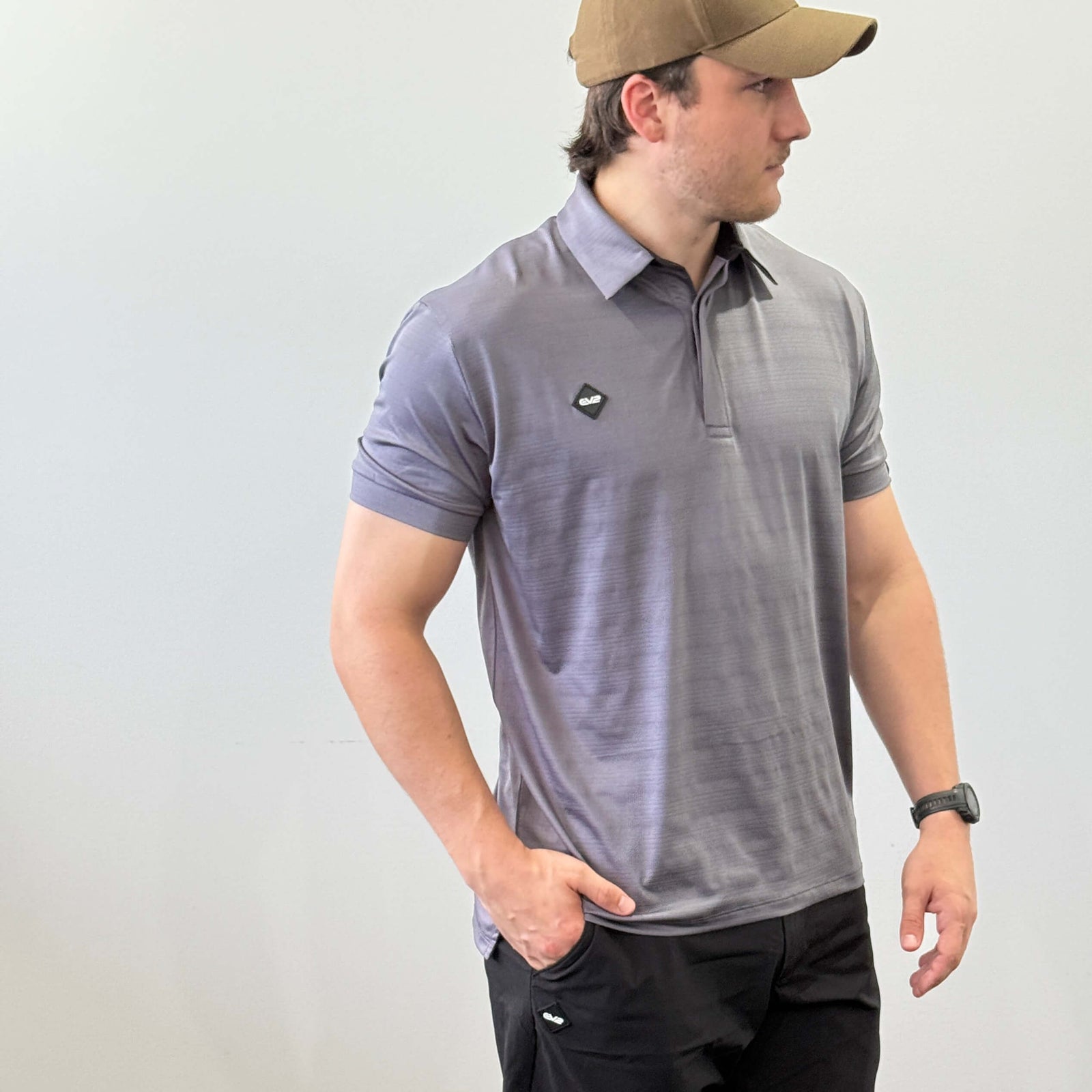 EV2 Masters Polo in Navy with a black rubber logo in the shape of a diamond. Model is also wearing black EV2 golf shorts.