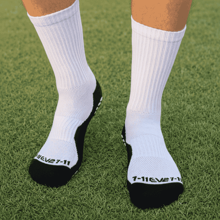 EV2 White Grip Socks  with Black sole on grassy field pictured from top of the foot. 