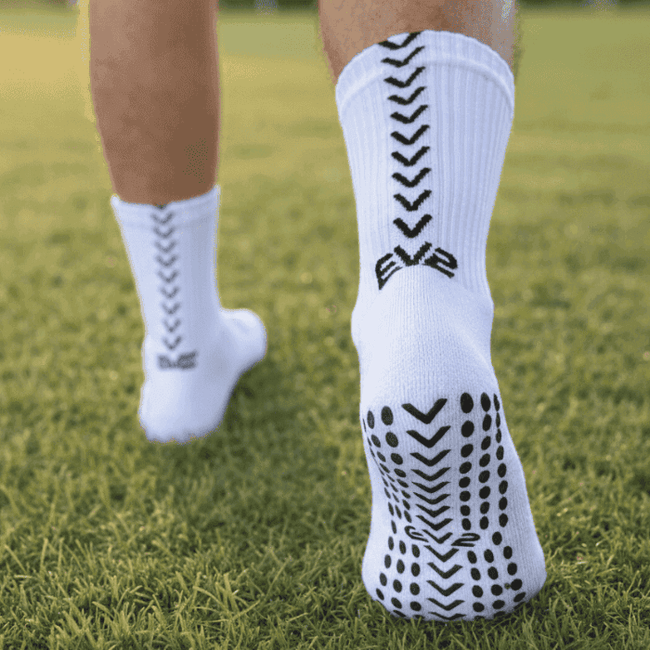 EV2 White Grip Socks on grassy field pictured from the sole of the foot