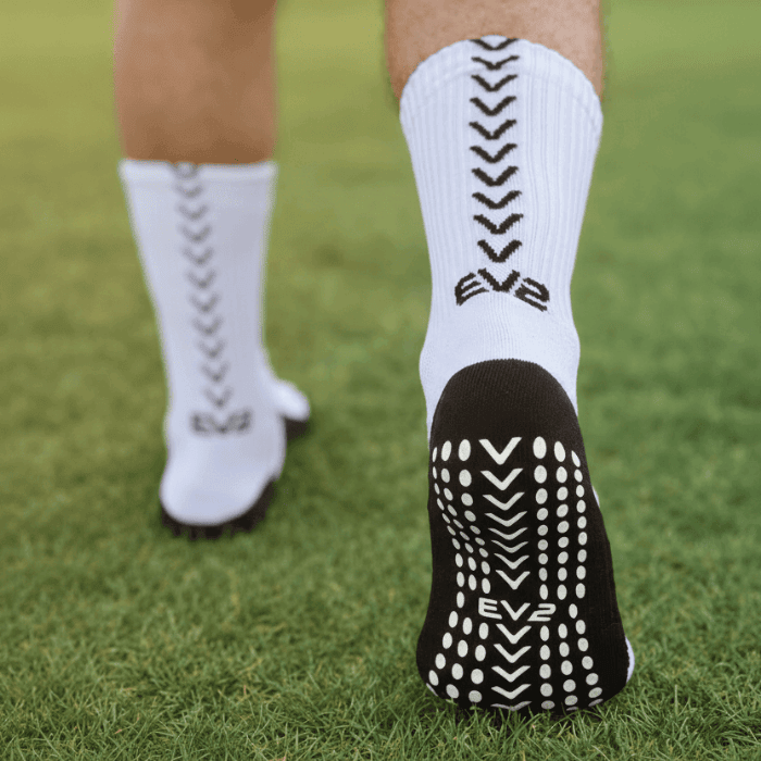 EV2 White and Black Grip Socks on grassy field pictured from the sole of the foot
